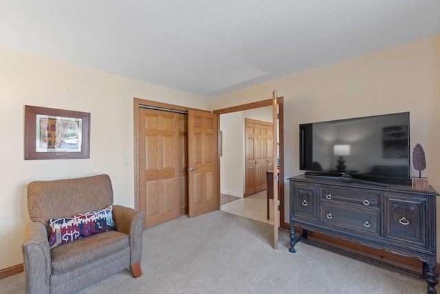 living area featuring baseboards and light colored carpet