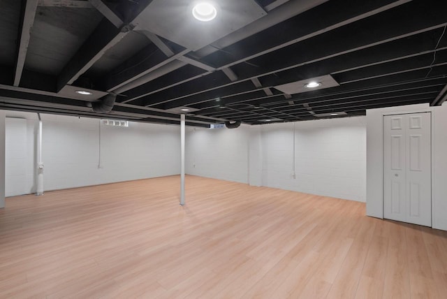 finished basement featuring wood finished floors and concrete block wall