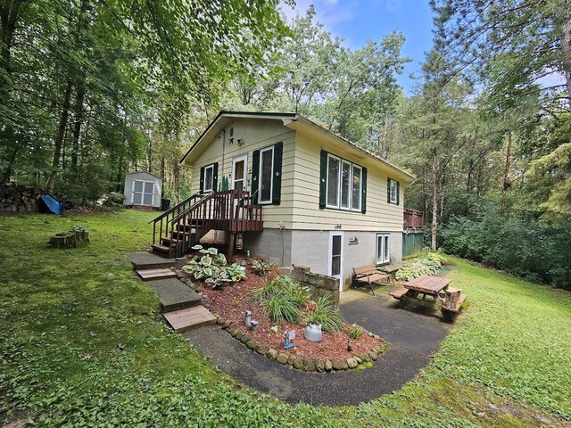 W5691 Cedar Trl, Neshkoro, WI 54960 - view of home's exterior featuring a lawn, a storage unit, an outbuilding, and a patio