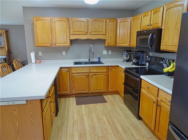 N1698 945th St, Eau Claire, WI 54701 - kitchen with a sink, black appliances, light wood-style floors, light countertops, and a peninsula