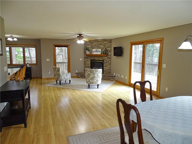 N1698 945th St, Eau Claire, WI 54701 - dining room with baseboards, light wood-style flooring, a stone fireplace, and a ceiling fan