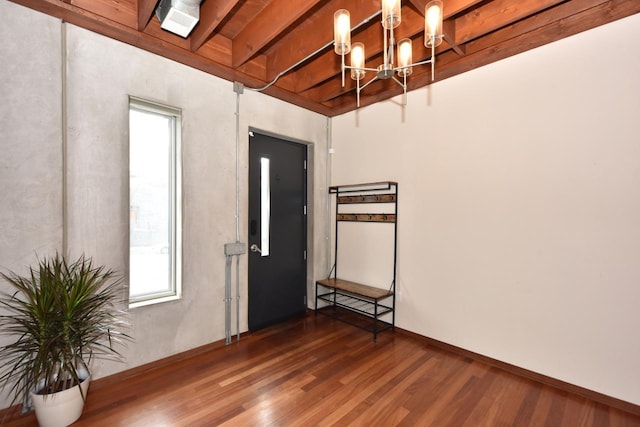empty room with a healthy amount of sunlight, wood finished floors, and a chandelier