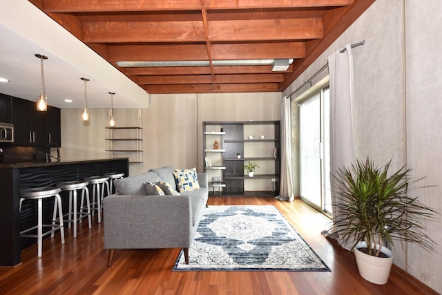 living area featuring beamed ceiling and wood finished floors