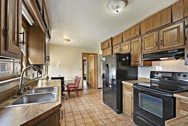 7709 3rd Ave, Kenosha, WI 53143 - kitchen with under cabinet range hood, a sink, light tile patterned floors, black appliances, and tasteful backsplash