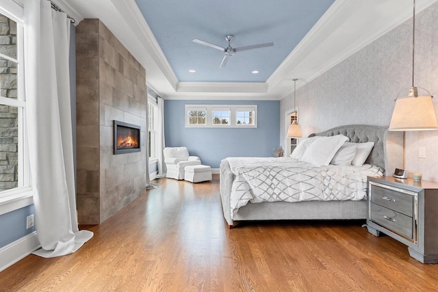 6916 N Palladium Ct, Appleton, WI 54913 - bedroom with a tiled fireplace, dark wood-type flooring, a raised ceiling, crown molding, and a ceiling fan