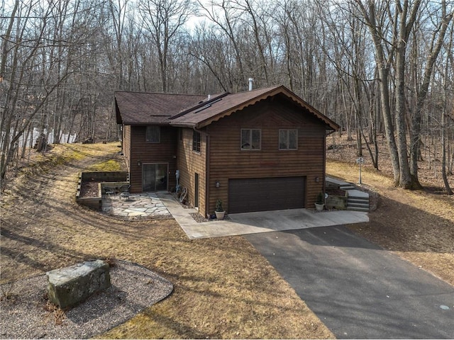 840 Park Dr, Balsam Lake, WI 54810 - view of property exterior with a forest view, a shingled roof, aphalt driveway, and a garage