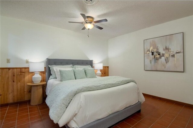 840 Park Dr, Balsam Lake, WI 54810 - tiled bedroom with wooden walls, a textured ceiling, ceiling fan, and wainscoting
