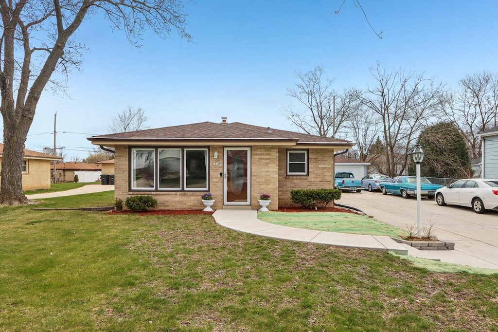 4428 S 47th St, Greenfield, WI 53220 - bungalow with brick siding, roof with shingles, and a front lawn