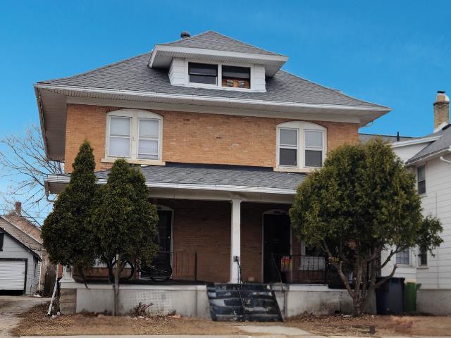 traditional style home with brick siding, roof with shingles, and covered porch