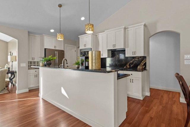 4923 W Woods Creek Ln, Appleton, WI 54913 - kitchen featuring arched walkways, appliances with stainless steel finishes, backsplash, and a center island with sink