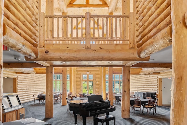 sitting room with log walls, a towering ceiling, and carpet