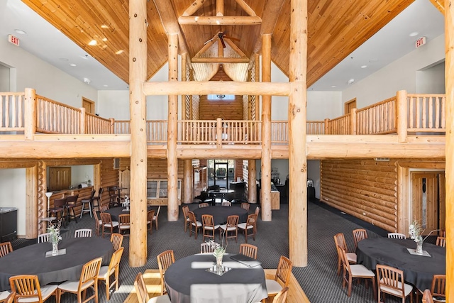 interior space with high vaulted ceiling, wooden ceiling, log walls, and carpet flooring