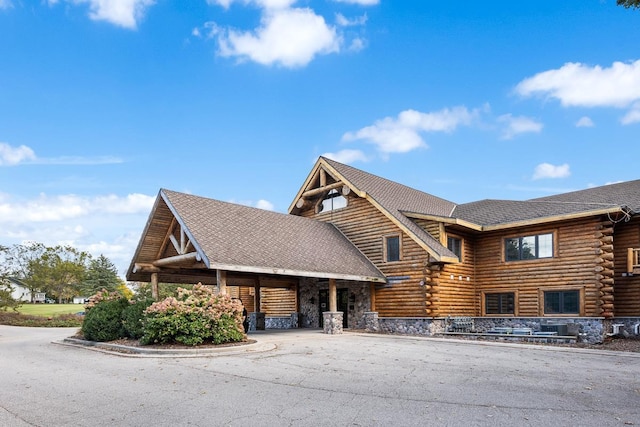 view of front of property featuring log exterior and roof with shingles