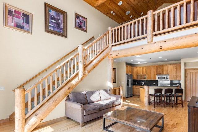 living area with recessed lighting, stairway, a towering ceiling, and light wood-type flooring