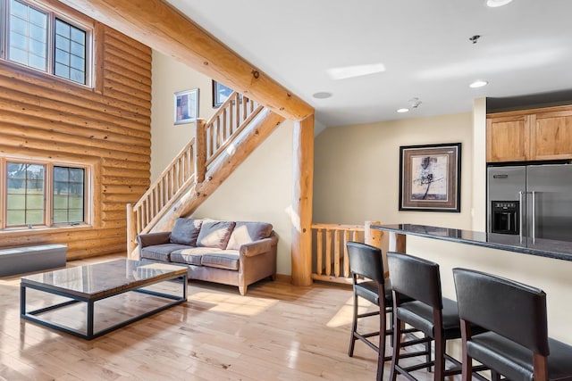 living area featuring rustic walls, light wood-style floors, a high ceiling, and recessed lighting