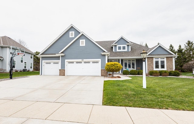 craftsman house featuring brick siding, an attached garage, driveway, and a front yard
