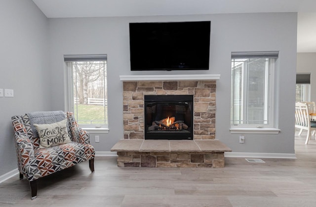sitting room featuring baseboards, wood finished floors, visible vents, and a fireplace