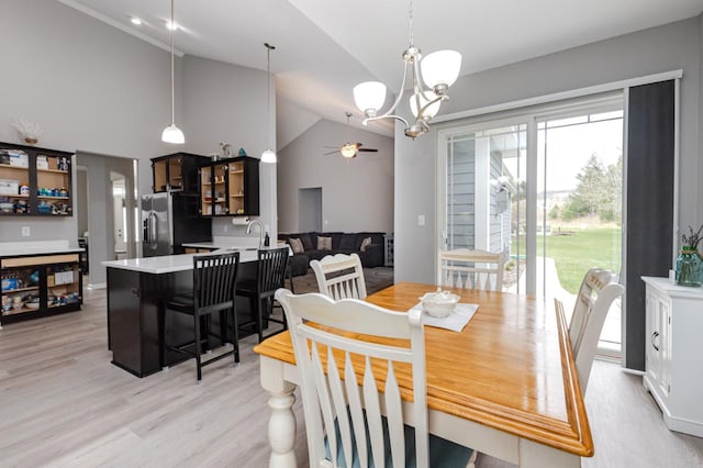 dining space featuring ceiling fan with notable chandelier, light wood-style flooring, and high vaulted ceiling