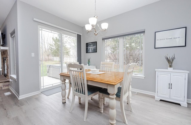 dining space featuring a notable chandelier, baseboards, a healthy amount of sunlight, and light wood-style flooring