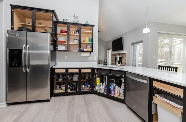 kitchen with appliances with stainless steel finishes, a sink, light countertops, and light wood-style flooring