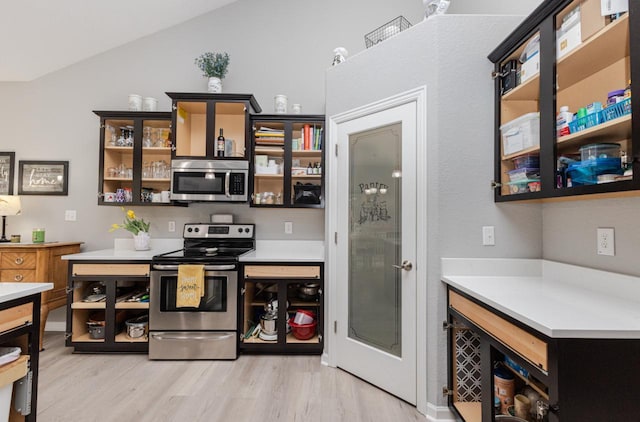 kitchen with light countertops, light wood-style floors, glass insert cabinets, and appliances with stainless steel finishes