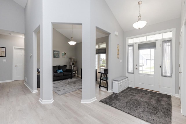 foyer entrance with high vaulted ceiling and light wood-style flooring