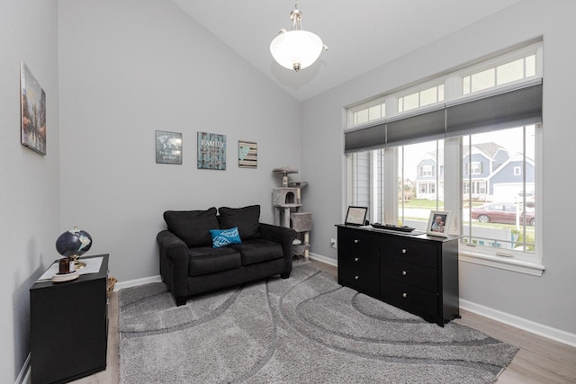 living area with baseboards, high vaulted ceiling, and light wood-style floors