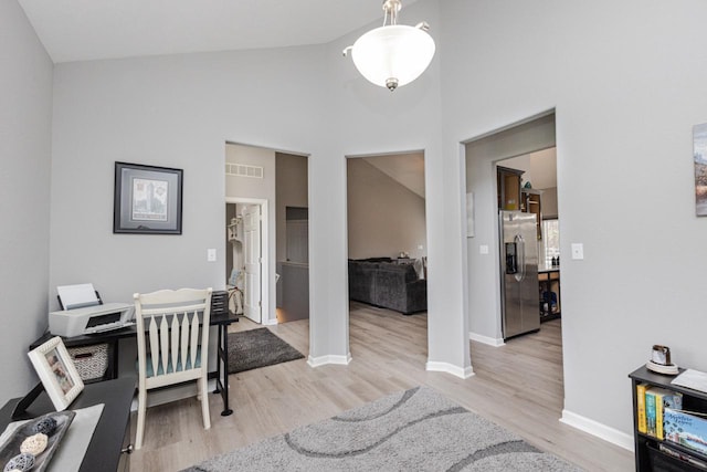 office area featuring baseboards, light wood-type flooring, visible vents, and high vaulted ceiling