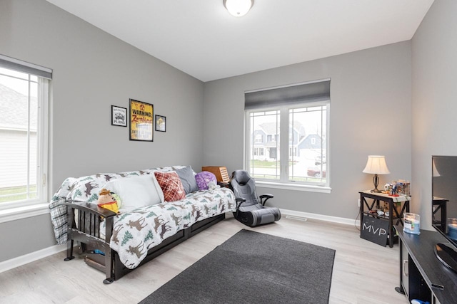 living room featuring baseboards, light wood-style floors, and visible vents
