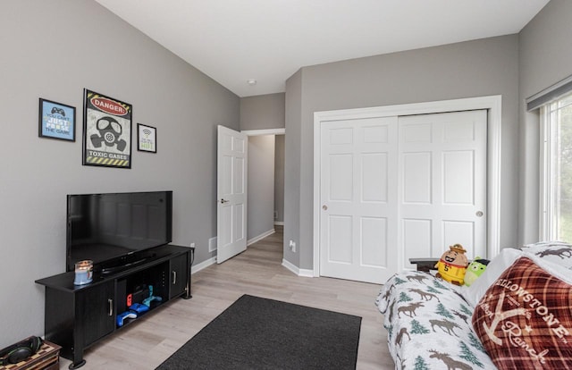 bedroom with baseboards, light wood finished floors, and a closet