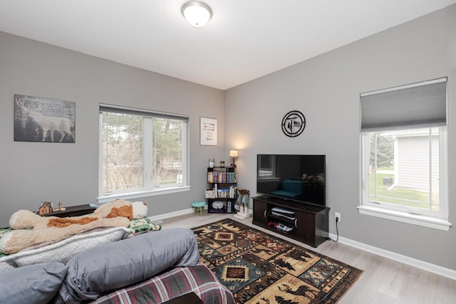 living room with baseboards, light wood-type flooring, and plenty of natural light