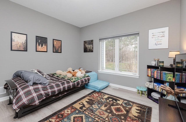 bedroom with wood finished floors, visible vents, and baseboards