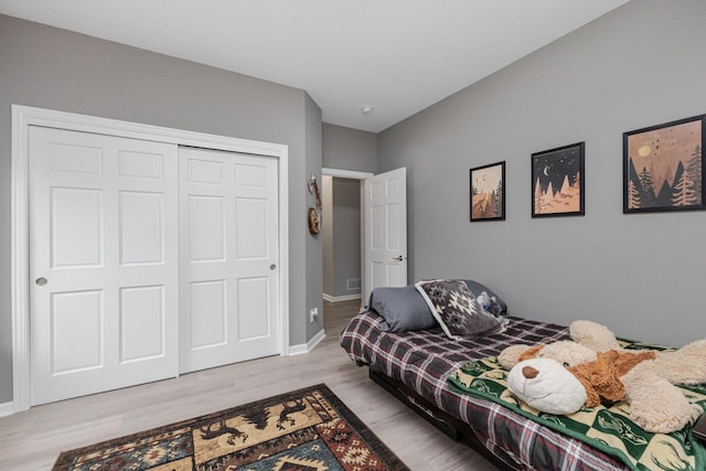 bedroom featuring baseboards, wood finished floors, and a closet