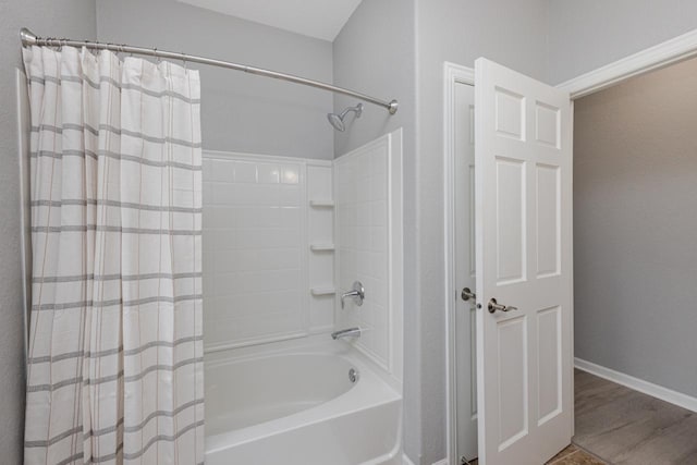 full bath featuring wood finished floors, shower / bath combo with shower curtain, and baseboards