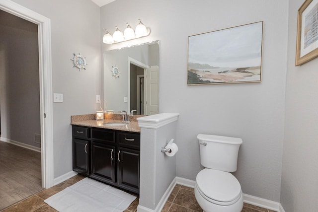 bathroom featuring tile patterned floors, baseboards, vanity, and toilet