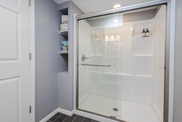 bathroom with baseboards, tile patterned flooring, and a stall shower