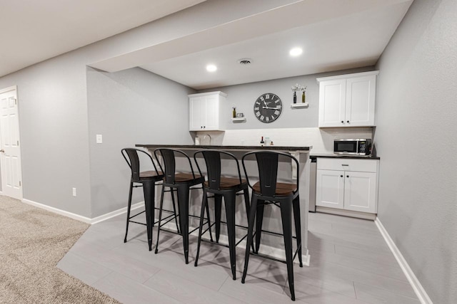 bar featuring stainless steel microwave, visible vents, baseboards, recessed lighting, and indoor wet bar