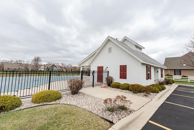 view of front of property with uncovered parking, a community pool, and fence