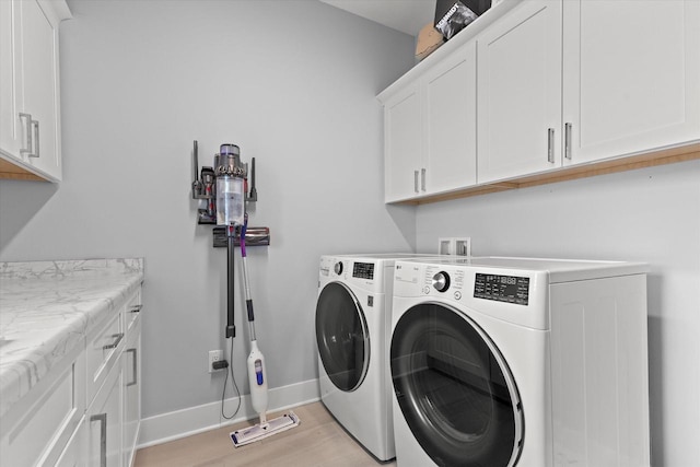 washroom with baseboards, light wood-style flooring, cabinet space, and washing machine and clothes dryer