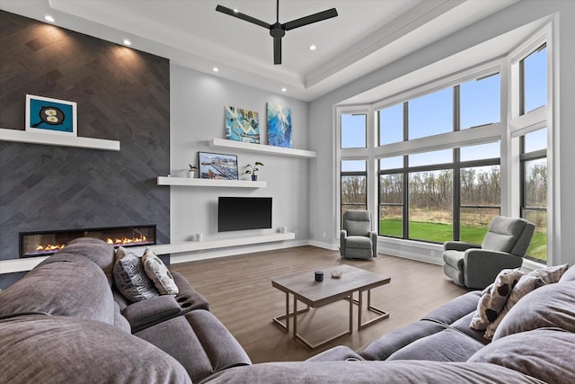living room featuring a ceiling fan, a large fireplace, wood finished floors, a high ceiling, and recessed lighting