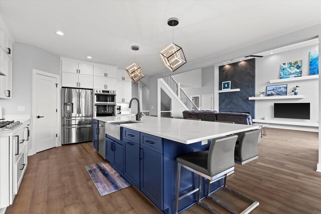 kitchen with blue cabinetry, dark wood-style flooring, appliances with stainless steel finishes, a sink, and white cabinets