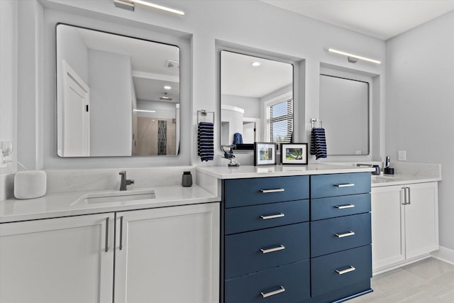 bathroom with a shower stall, two vanities, and a sink