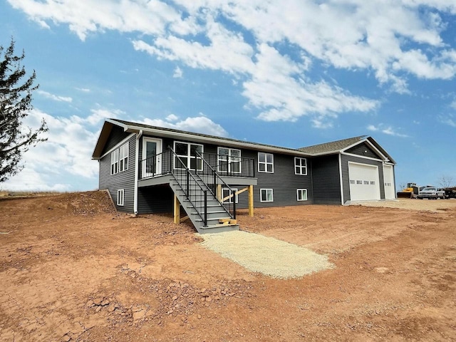 view of front facade with an attached garage, stairs, and dirt driveway