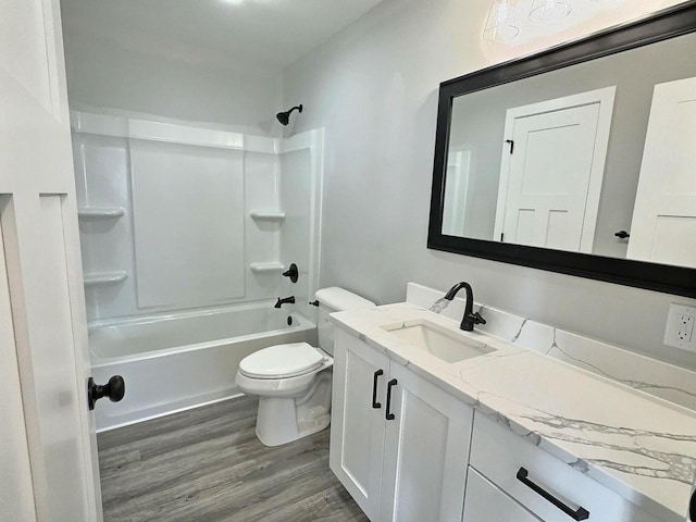 bathroom with wood finished floors, toilet, vanity, and shower / washtub combination
