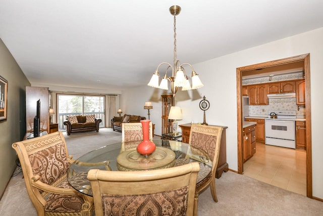 dining area with an inviting chandelier, light colored carpet, and light tile patterned floors