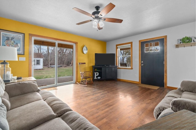 living room with baseboards, a ceiling fan, wood finished floors, and a textured ceiling