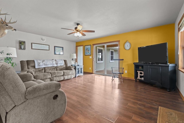 living area featuring dark wood finished floors, ceiling fan, and baseboards