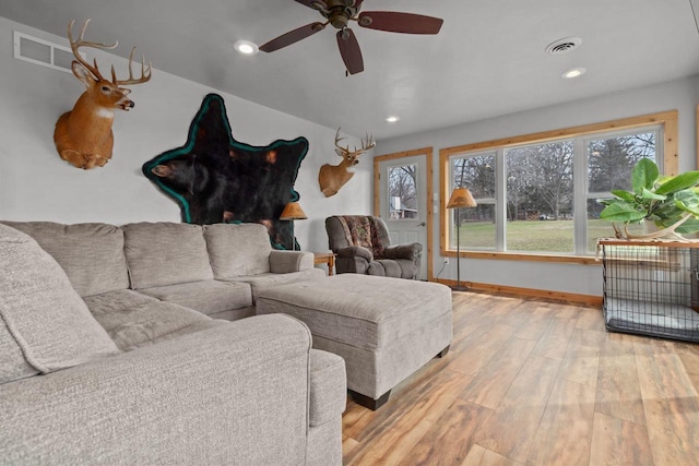 living room featuring light wood-type flooring, baseboards, visible vents, and ceiling fan