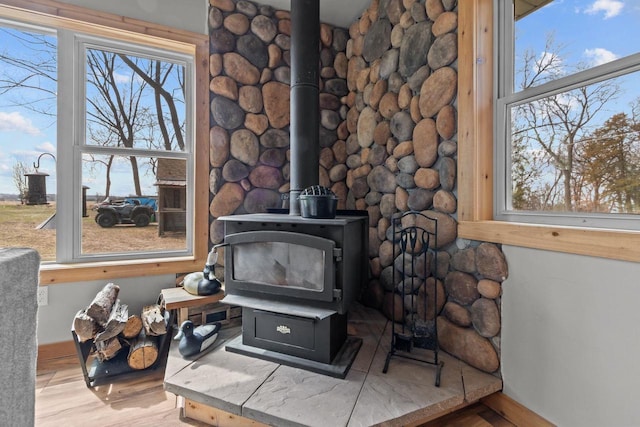 room details with wood finished floors, a wood stove, and baseboards