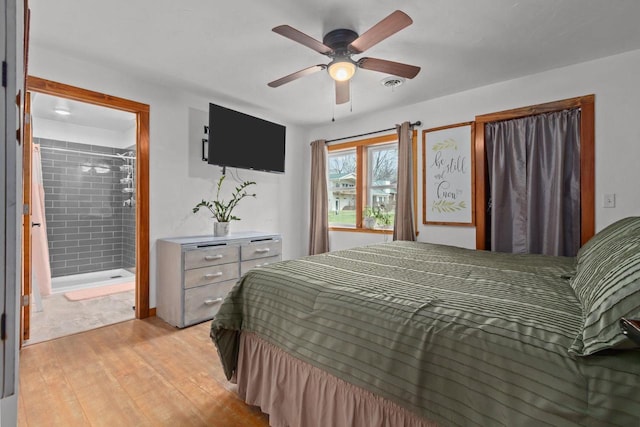 bedroom featuring light wood-type flooring, a ceiling fan, visible vents, and connected bathroom